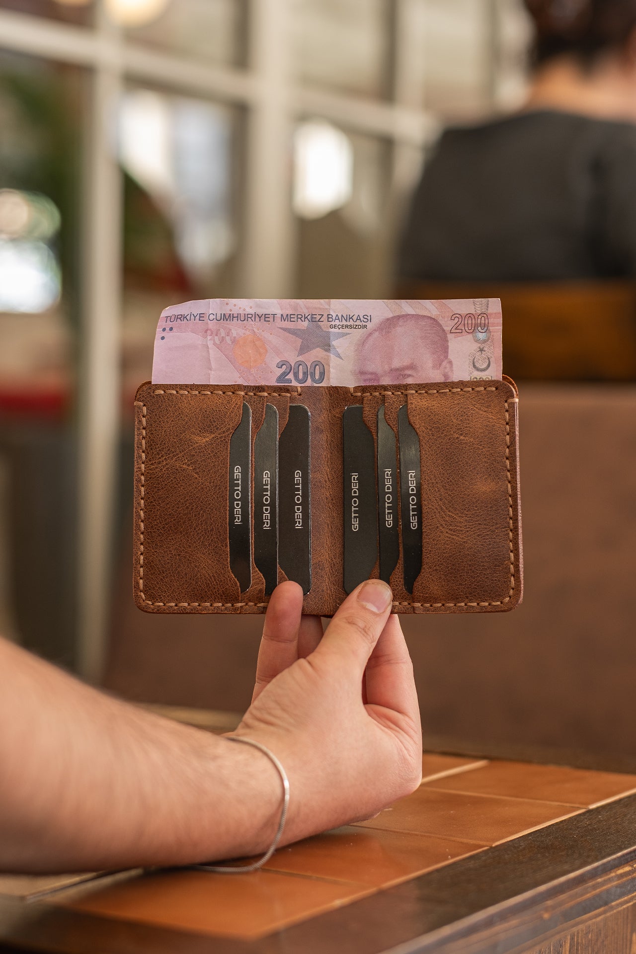 Kahverengi deri kartlık, içinde 200 TL banknot ve kartlar