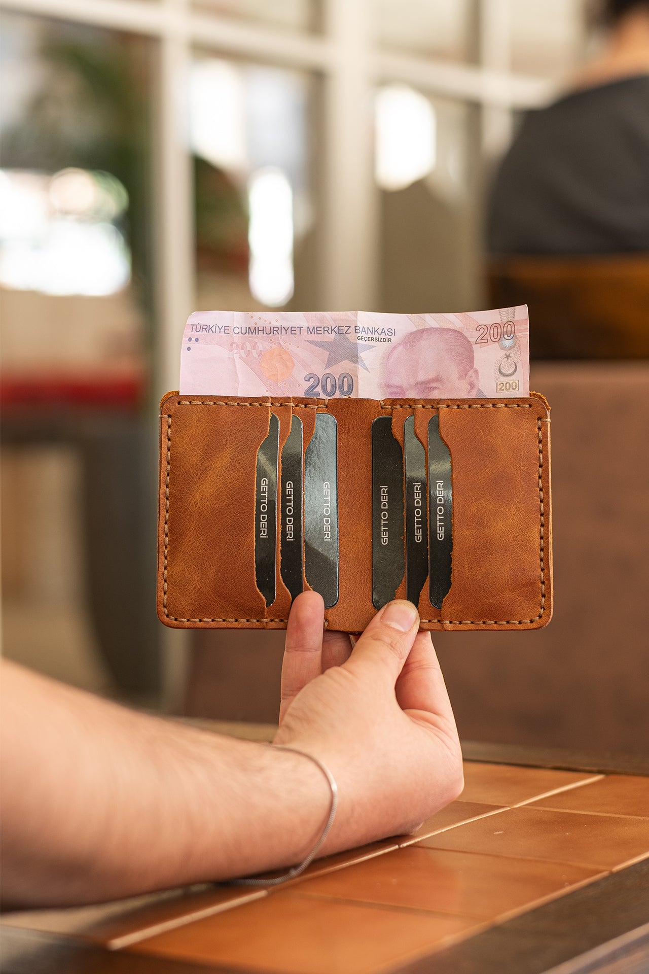 Kahverengi deri kartlık, içinde kartlar ve 200 TL banknotu