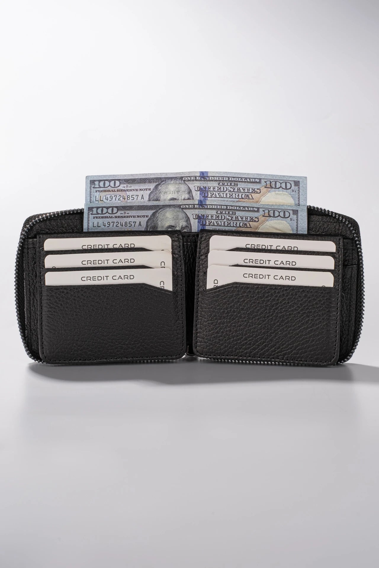 Siyah deri cüzdan, kredi kartları ve 100 dolarlık banknotlarla dolu