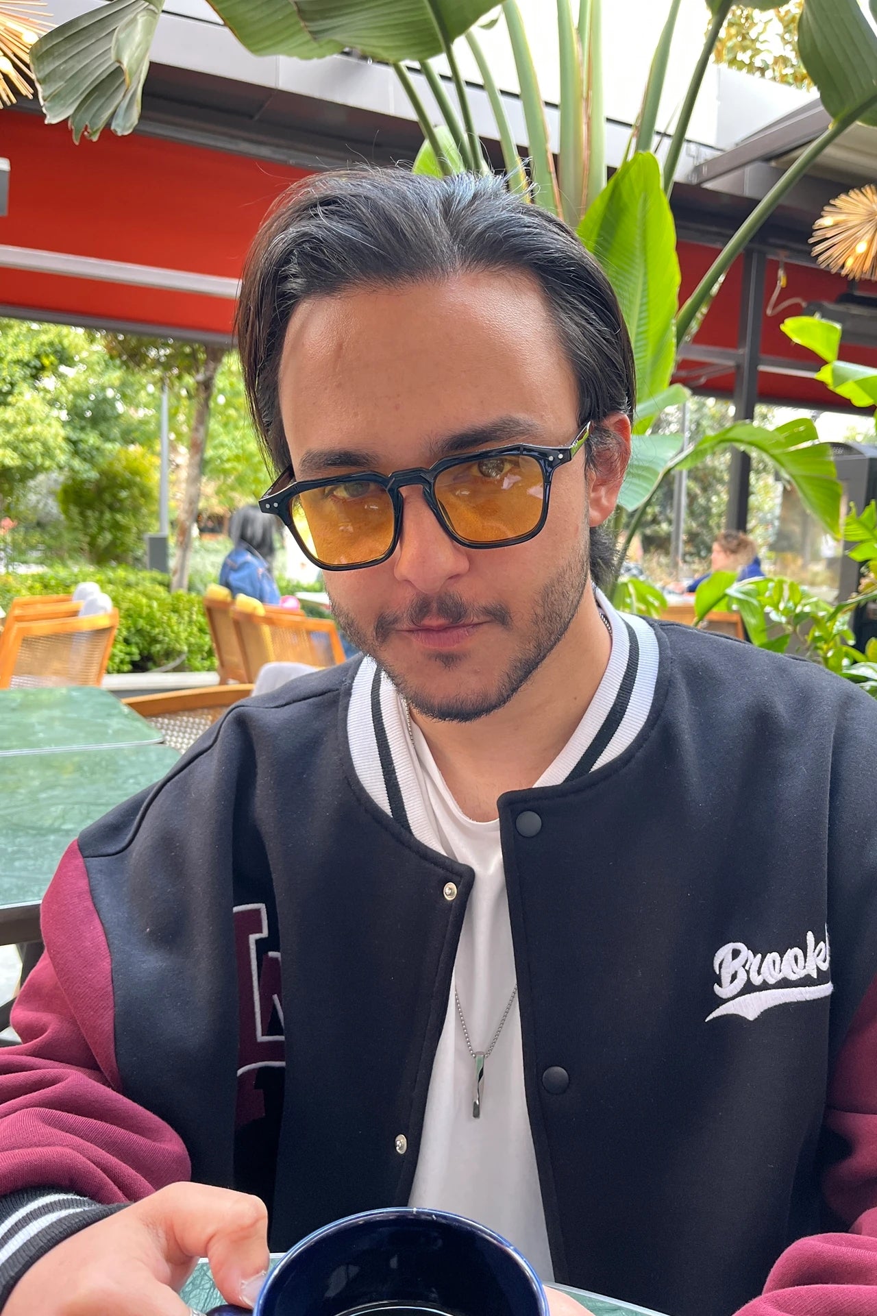 Sarı lensli siyah çerçeveli güneş gözlüğü, dış mekan kahve masasında