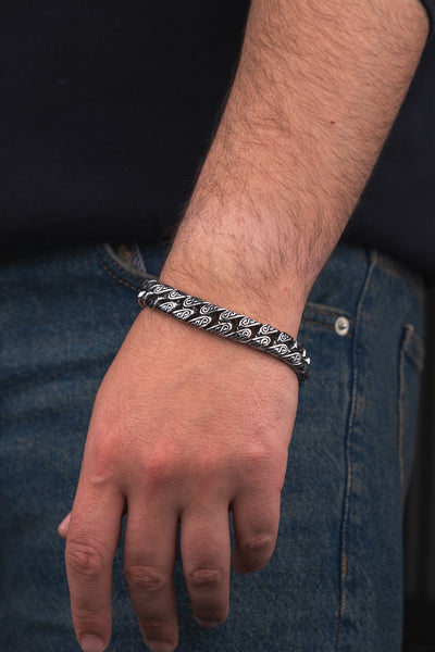 Gümüş rengi, desenli metal bileklik erkek kolunda