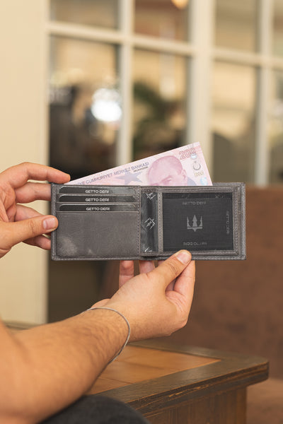 Siyah deri cüzdan, kartlık ve para bölmesiyle açık tutuluyor