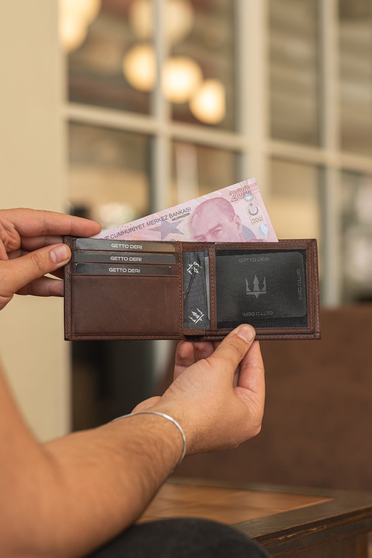 Kahverengi deri cüzdan, kartlık ve para bölmesiyle açık tutuluyor
