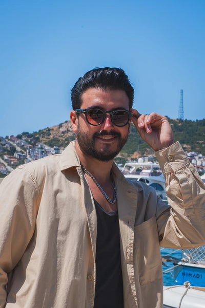 Güneş gözlüğü takan adam, açık mavi gökyüzü ve deniz manzarası önünde