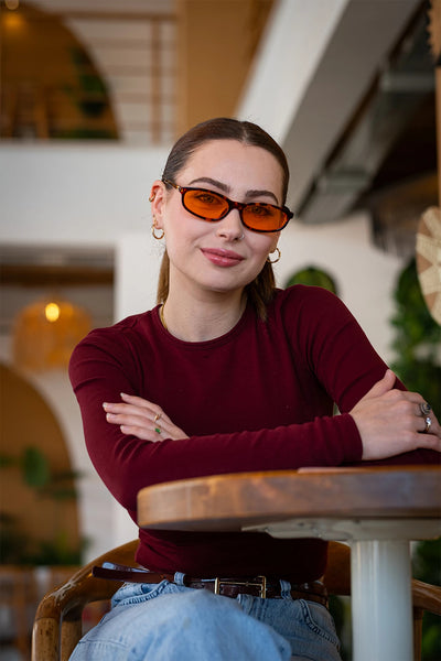 Kadın kahverengi deri kemer, mavi kot pantolon ve kırmızı uzun kollu tişört giymiş