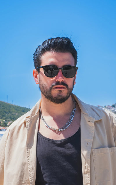 Güneş gözlüğü takan adam, açık mavi gökyüzü önünde