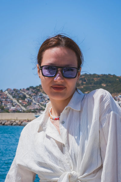 Siyah çerçeveli mor lensli güneş gözlüğü, deniz manzaralı yazlık stil