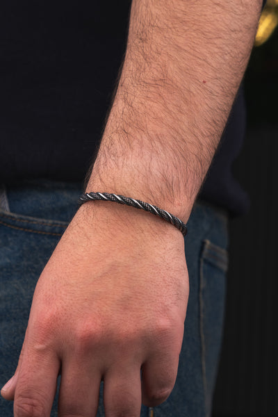 Gri tonlu örgü desenli metal bileklik erkek kolunda